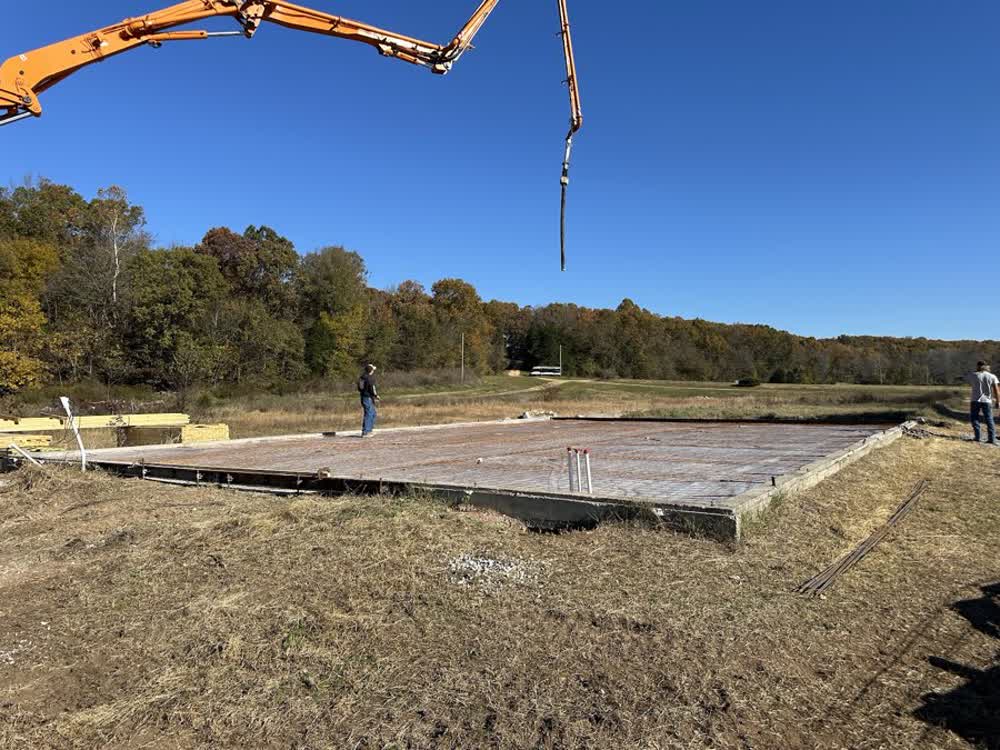 Concrete crew placing a large formed slab with a boom pump on a rural Missouri lot